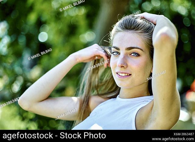 Portrait of a young beautiful caucasian woman in her 20's with long hair and blue eyes outdoor in a garden. Lifestyle concept