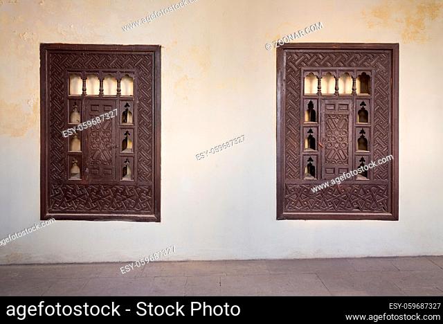 Two wooden arabesque ottoman era cupboards with engraved decorations embedded in a grunge wall