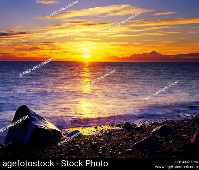 Sunset over Cook Inlet with Iliamna Volcano in Lake Clark National Park on the horizon. View from shore south of Anchor Point, Kenai Peninsula, Alaska