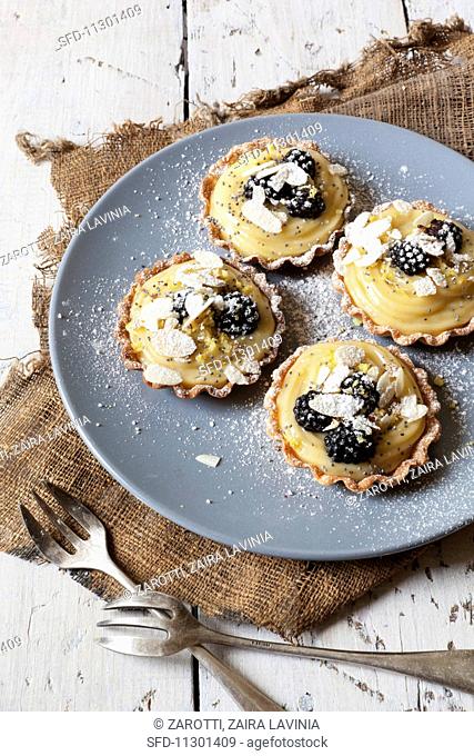 Blackberry tartlets with lemon cream, flaked almonds and icing sugar