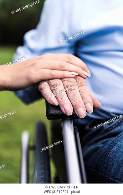 Young woman touching senior man's hand, close-up