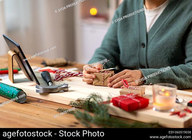 woman with tablet pc packing christmas gift