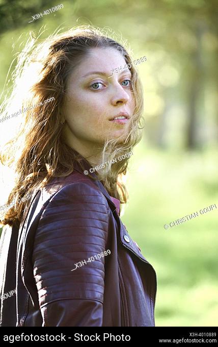 Jeune femme portant un blouson de cuir, de profil. Departement d'Eure-et-Loir, region Centre-Val-de-Loire, France, Europe / Young woman wearing a leather jacket