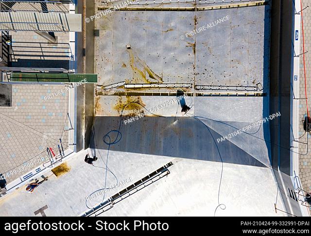 PRODUCTION - 21 April 2021, Bavaria, Munich: Employees clean a large pool at Westbad before the start of the outdoor pool season