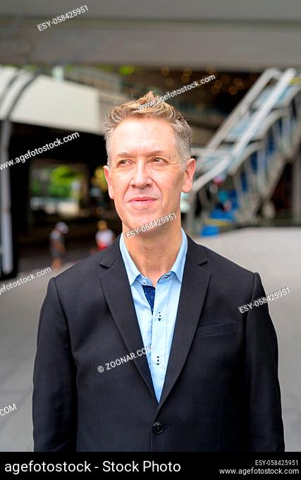 Portrait of mature businessman in suit at footbridge in the city