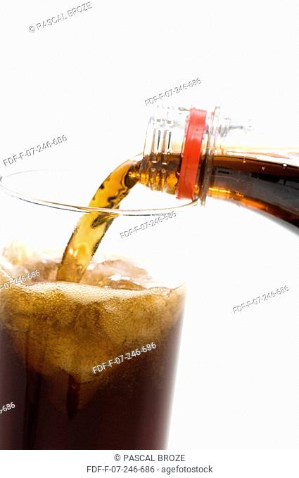 Close-up of cola being poured into a glass from a bottle