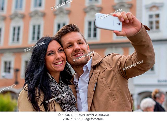 Ein junges Paar macht ein Selbstporträt mit einem Handy. Selfies sind in