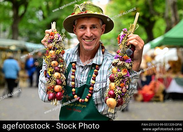 13 October 2023, Thuringia, Weimar: Udo Pötzschke, onion farmer from Heldrungen, presents onion braids at the start of the 370th Weimar Onion Market
