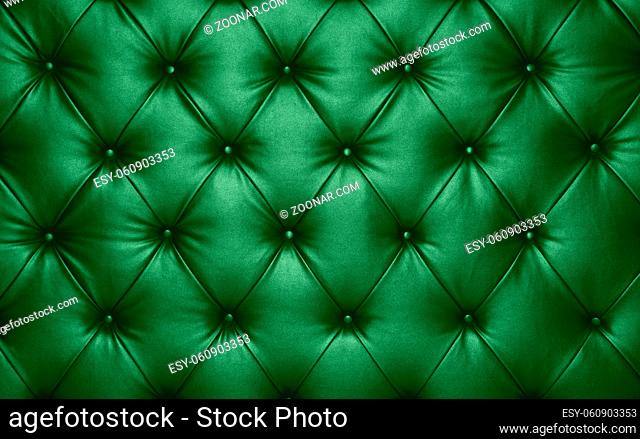 Close up background texture of dark green capitone genuine leather, retro Chesterfield style soft tufted furniture upholstery with deep diamond pattern and...