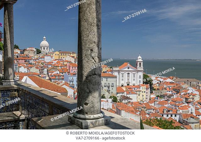 The columns on a terrace frame terracotta roofs and the ancient dome at Miradouro Alfama Viewpoint of Lisbon Portugal Europe