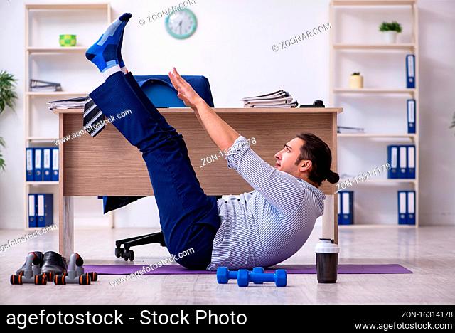 Handsome male employee doing exercises in the office