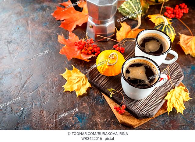 Autumn still life with enamel cups with coffee, pumpkins and maple leaves