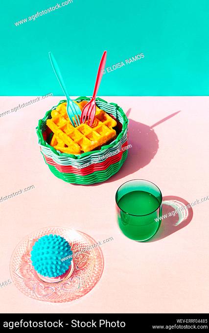 Waffle in basket, juice and rubber ball kept on table