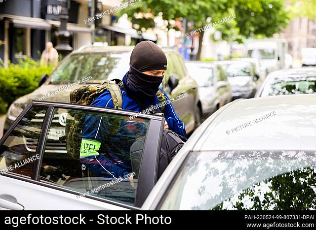 24 May 2023, Berlin: A police officer loads a bag into a vehicle during a house search in Berlin-Kreuzberg. Police and public prosecutors searched 15 properties...