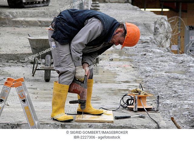 Construction worker drilling a hole into a concrete slab