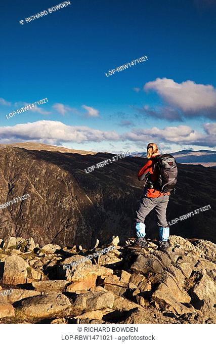 England, Cumbria, Buttermere. A young woman standing on the sumit of a mountain in the Lake District