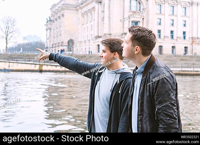 two male tourists exploring government district with Reichstag building and Spree river in Berlin Germany