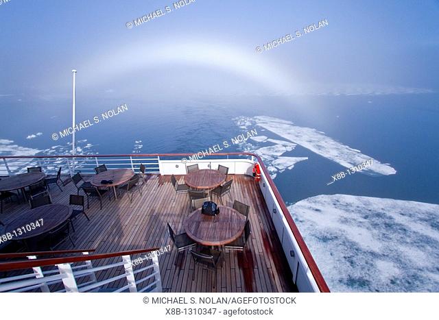 Fog and a fog bow surround the Lindblad Expeditions ship National Geographic Explorer in Palanderbutka, Nordaustlandet, in the Svalbard Archipelago
