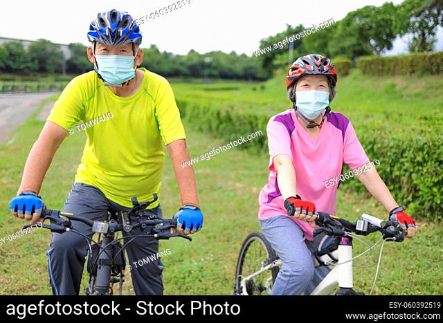 Asian Senior couple wearing medical mask and riding bicycle in the park