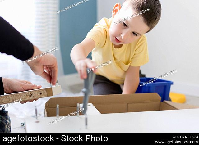 Boy helping father assembling table at home
