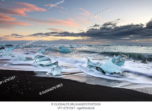 a cold winter sunset in Jokulsarlon beach in mid-december, at low tide. the long exposure enhances the wave pattern