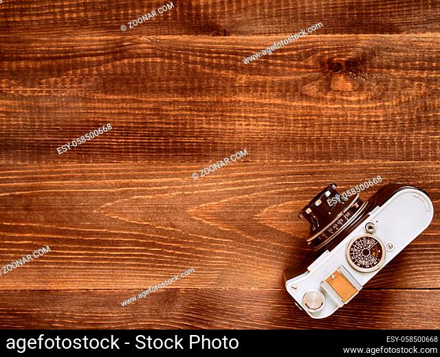 Wooden table background with old vintage camera. Flat lay or top view