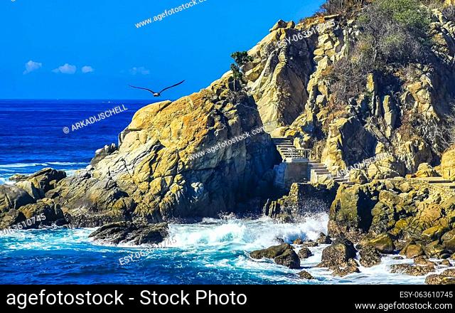 Blue turquoise water and extremely beautiful huge big surfer waves rocks cliffs stones mountains and boulders on the beach in Zicatela Puerto Escondido Oaxaca...