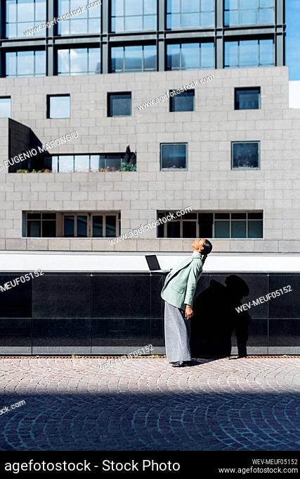 Businesswoman bending backward by office building