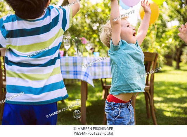 Children trying to catch soap bubbles in garden