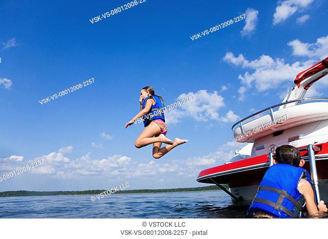 USA, Missouri, Stockton, Stockton Lake, girl 8-9 jumping off boat, boy 6-7 watching