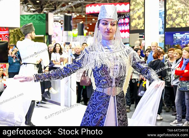 RUSSIA, MOSCOW - 12 de NOVIEMBRE, 2023: Una mujer con traje tradicional realiza un baile folclórico en un stand de la República de Ossetia-Alania del Norte...