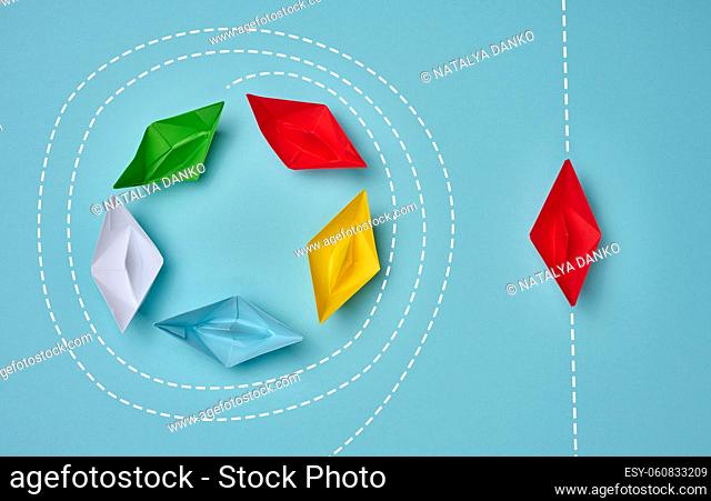 a group of paper boats floats in a circle, another red floats in a straight line. Strong leader concept, different vision, strong business