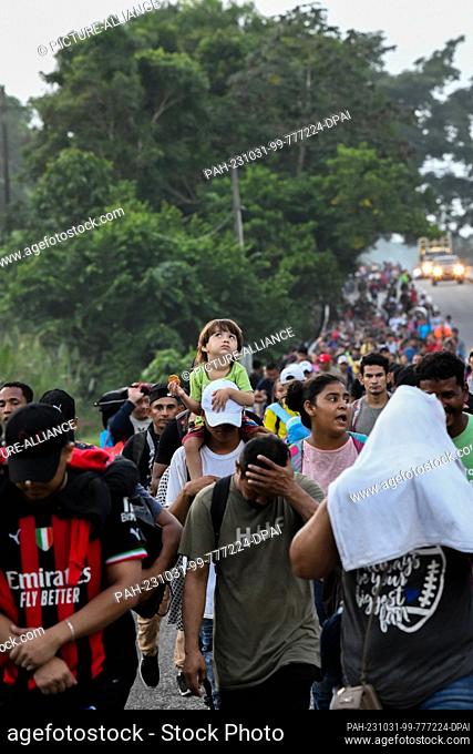 31 October 2023, Mexico, Chiapas: A child looks up to the sky while being carried on his shoulders in the midst of a migrant caravan