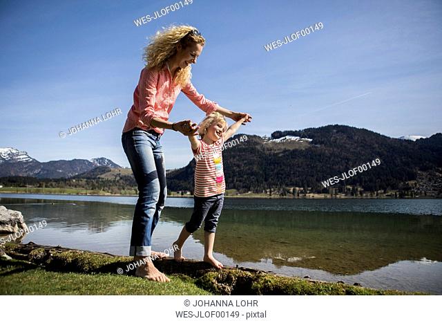 Austria, Tyrol, Walchsee, happy mother and daughter walking at the lake