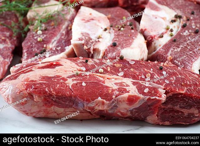 Plain fresh beef cut chuck steak and raw steaks with bone on cutting board prepared for cooking