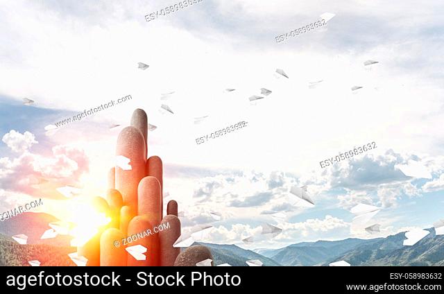 Image of high and huge stone columns located outdoors among flying paper planes with beautiful landscape on background. Wallpaper, backdrop with copyspace