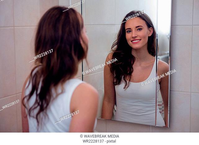 Beautiful brunette posing in front of the bathroom mirror