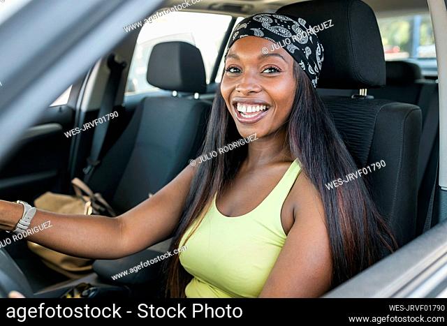 Happy woman wearing headscarf sitting in car