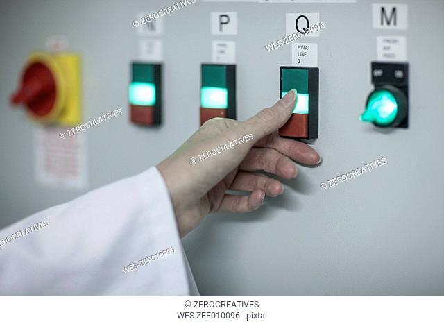 Close-up of woman switching on power switch in factory