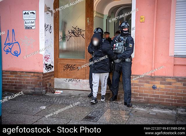 07 December 2022, Berlin: Police officers lead a man out of an apartment building in Schöneberg this morning. Since the morning