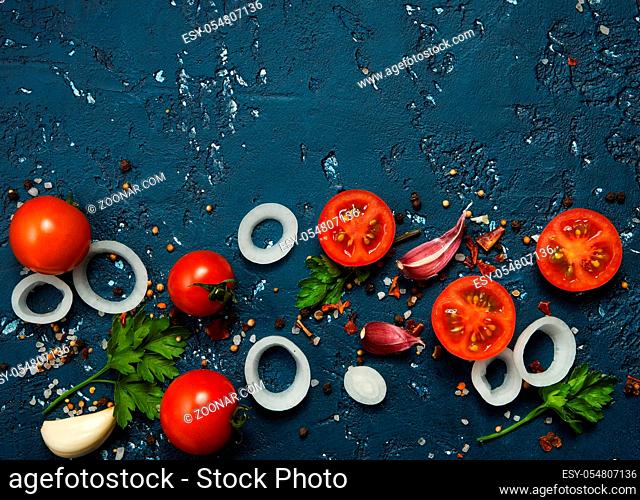 Vegetables background. Fresh vegetables (garlic, tomatoes, onions) on a dark embossed surface. View from above. Copy space