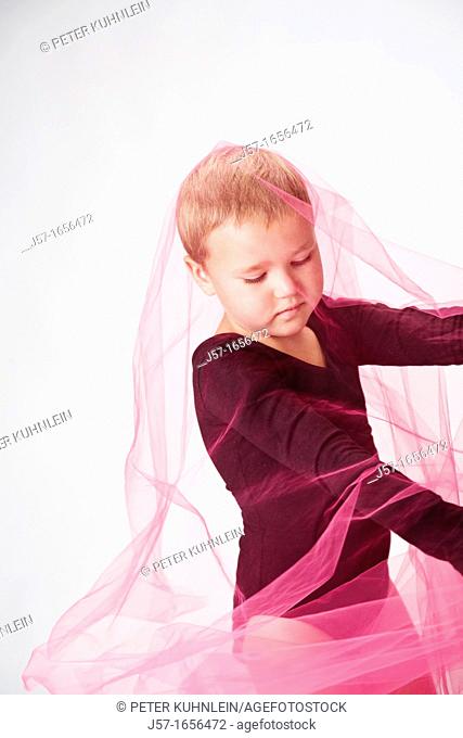 Young girl in a black leotard with pediatric cancer leukimia playing with fabric in the studio