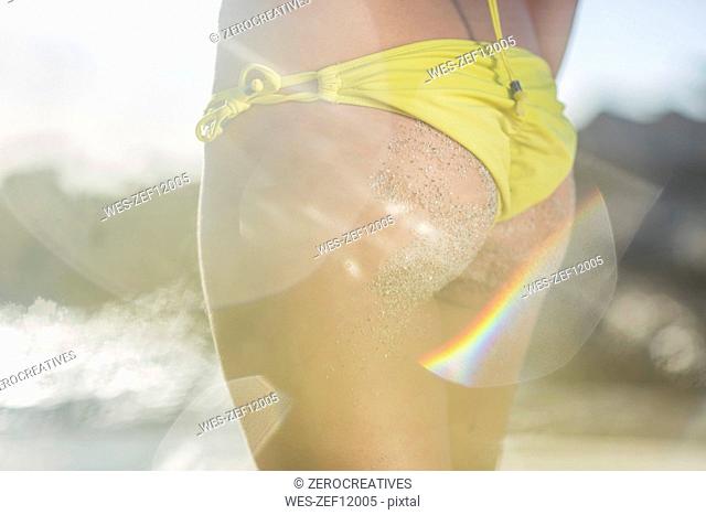 Close-up of young woman wearing yellow tanga on the beach