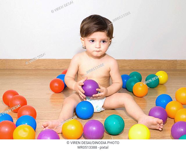 Baby wearing diaper playing with colourful balls , MR779N