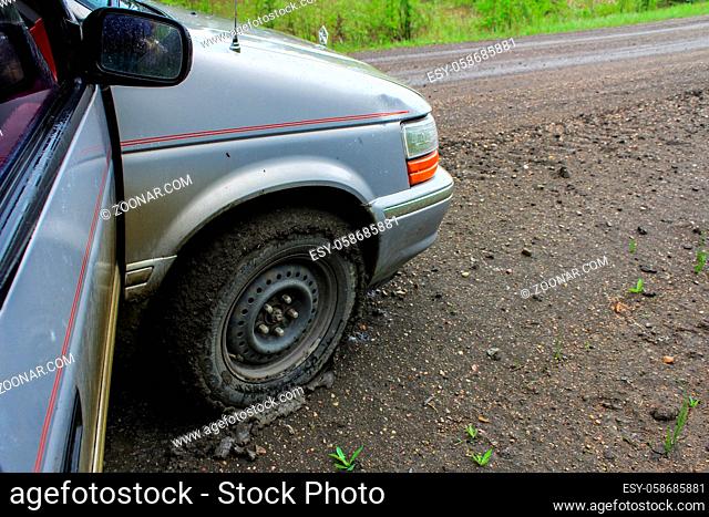 driving on a wet clay road. Closeup picture on the front right wheel of the vehicle, fully surrounded by a thin layer of clay