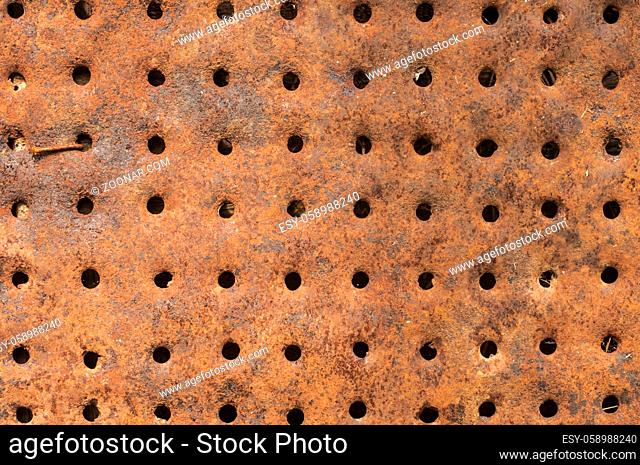 Old rusty weathered corroded iron metal tin surface with holes closeup as background