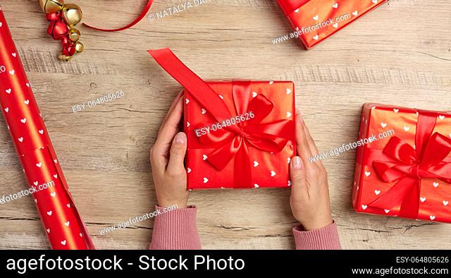 Christmas decor, gifts wrapped in red paper on a wooden background, top view