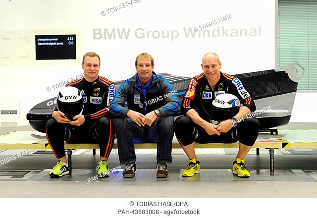 Francesco Friedrich (L), Alexander Mann and German national coach Christoph Langen (C) pose next to the FES-208 two men bobsled in a wind tunnel at the...