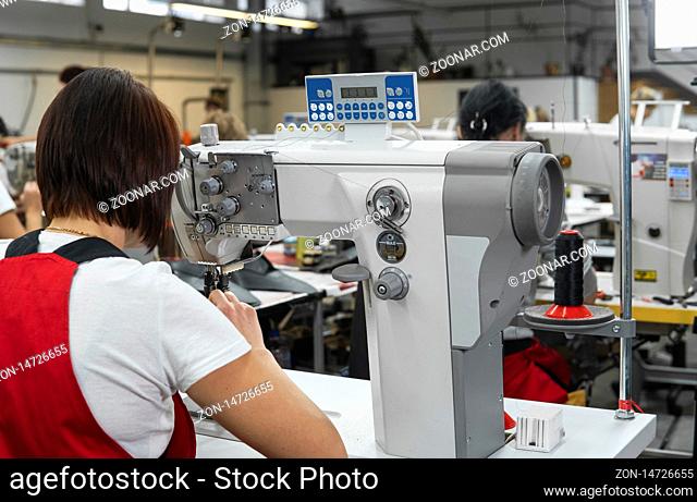 Dressmaker woman working with sewing machine on a shoes factory