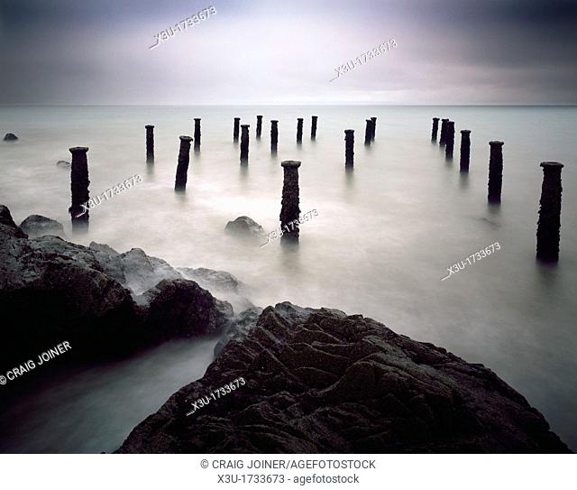The pillars of the old pier under a grey stormy sky at Westward Ho! on the North Devon coast, England, United Kingdom